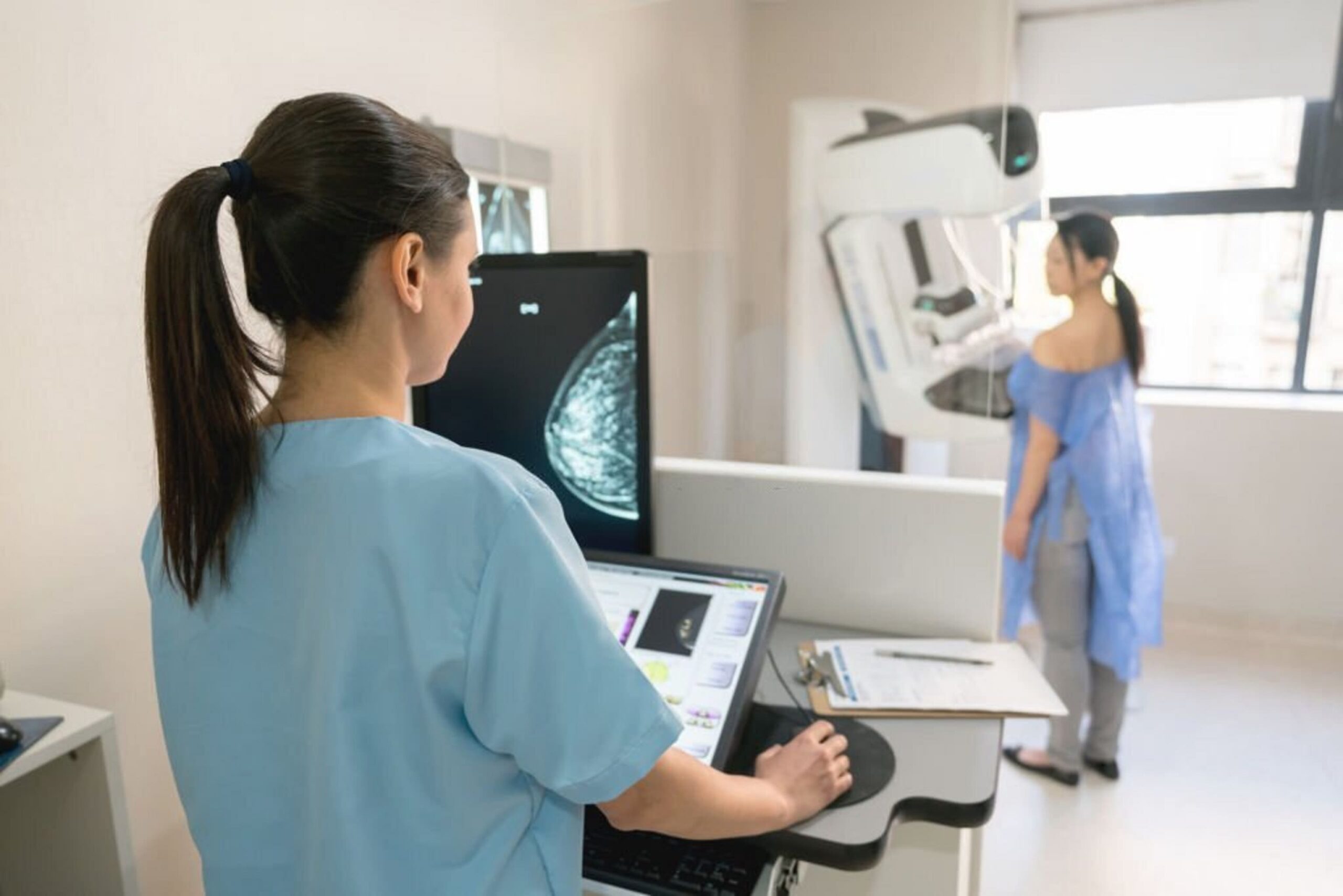 A female doctor taking images of her patient during a mammogram procedure
